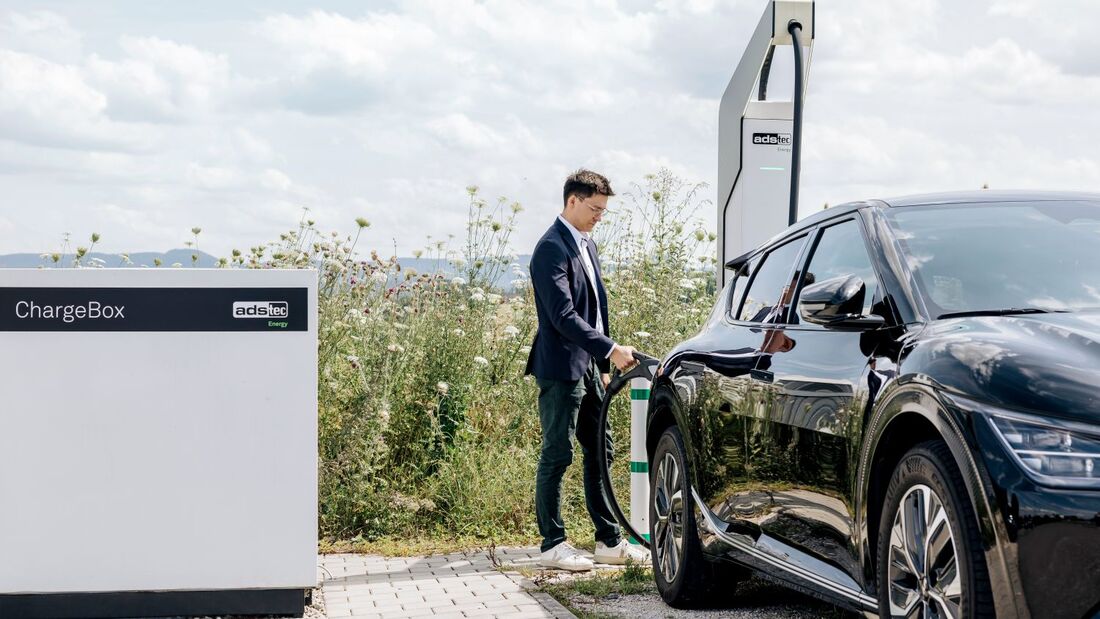 Person lädt ein Elektroauto an einer ChargeBox von ADS-TEC Energy im Außenbereich.