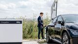 Person lädt ein Elektroauto an einer ChargeBox von ADS-TEC Energy im Außenbereich.