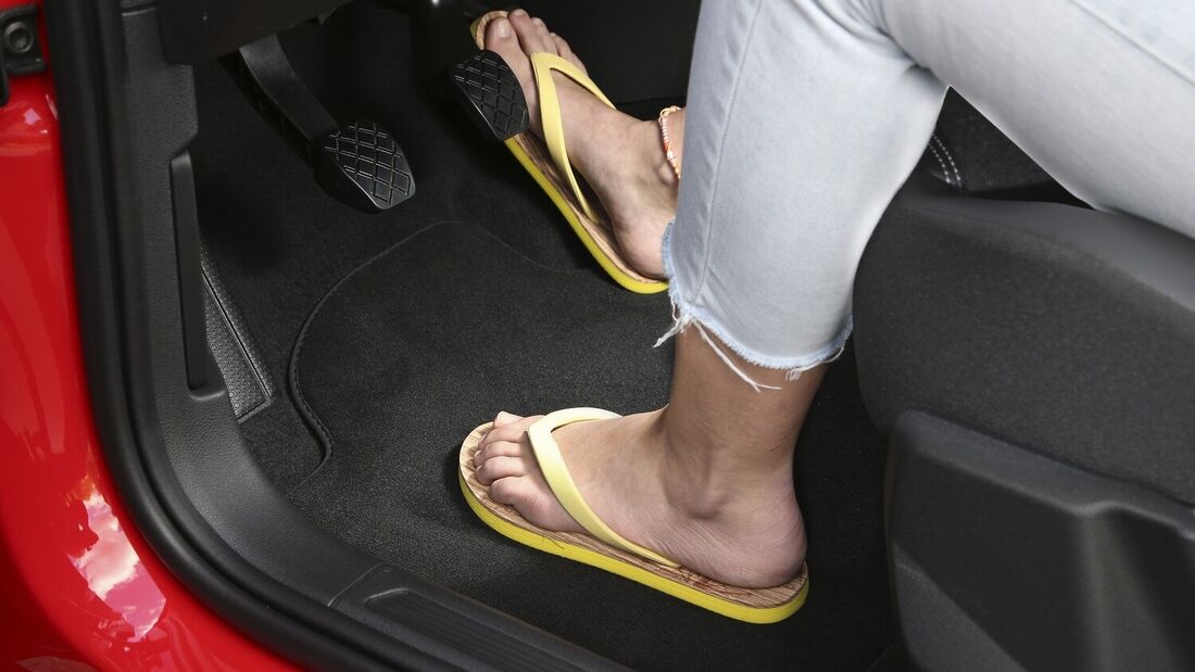 Person mit Flip-Flops bedient die Pedale eines Autos während der Fahrt.