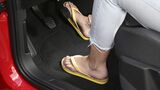 Person mit Flip-Flops bedient die Pedale eines Autos während der Fahrt.
