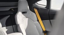 Polestar 5 Interieur: Rücksitz mit hellem Sportsitz und gelbem Sicherheitsgurt in moderner Innenraumgestaltung.