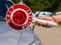 Polizeikontrolle im Straßenverkehr mit Anhaltekelle an einem Pkw zur Überprüfung der Fahreignung des Fahrers.