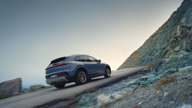 Porsche Cayenne S Electric fährt eine kurvige Bergstraße entlang, Heckansicht.ederausstattung und geöffnetem Fahrerbereich.