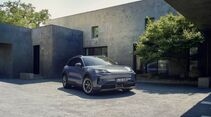 Porsche Cayenne S Electric steht vor moderner Architektur mit Betonfassade.