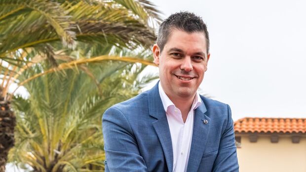 Porträt von Felix Gebhart, Vertriebschef von Mazda Deutschland, im Außenbereich vor Palmen.