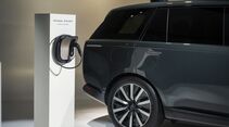 Range Rover Electric neben einem Range Rover Home Charger mit aufgewickeltem Ladekabel.