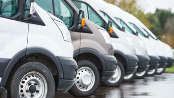 Reihe moderner Transporter einer Unternehmensflotte, relevant für neue Technikpflichten, CO2-Kosten und gesetzliche Vorgaben ab 2026.