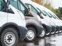 Reihe moderner Transporter einer Unternehmensflotte, relevant für neue Technikpflichten, CO2-Kosten und gesetzliche Vorgaben ab 2026.