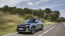 Renault 4 E-Tech Electric in grauer Lackierung während der Fahrt auf einer Landstraße mit bewaldeter Umgebung.