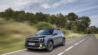 Renault 4 E-Tech Electric in grauer Lackierung während der Fahrt auf einer Landstraße mit bewaldeter Umgebung.