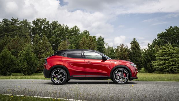 Roter Alfa Romeo Junior Veloce in Seitenansicht auf Straße vor Bäumen