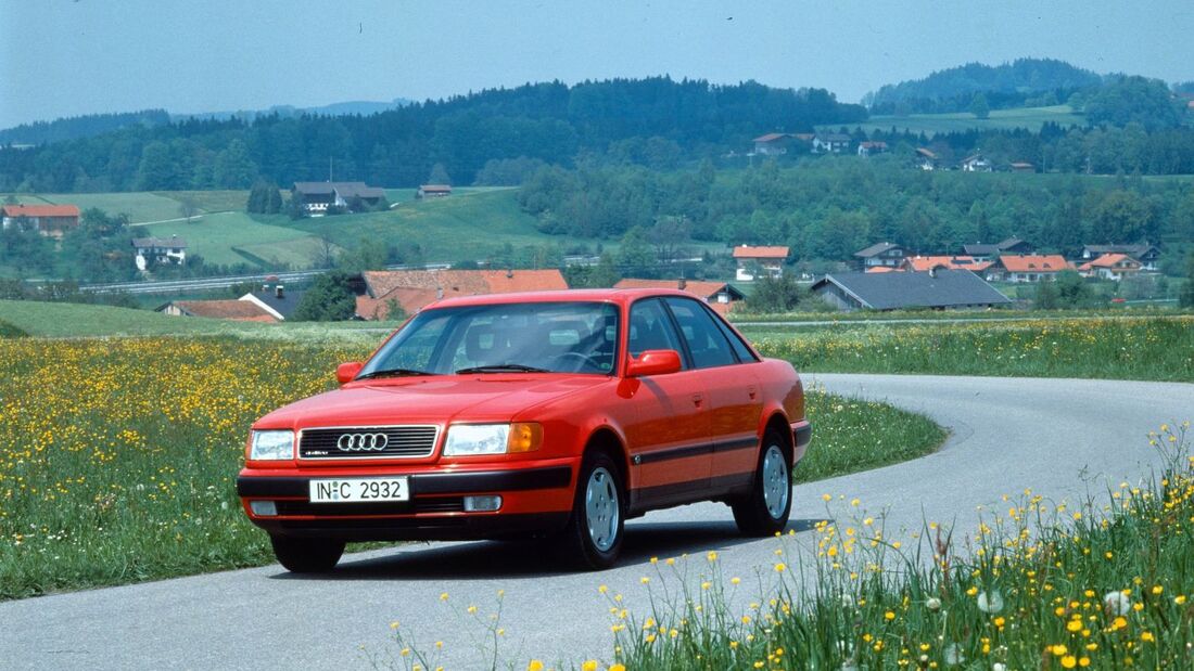 Roter Audi 100 C4 als Limousine mit Allradantrieb quattro auf kurviger Landstraße.