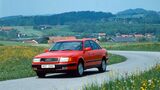Roter Audi 100 C4 als Limousine mit Allradantrieb quattro auf kurviger Landstraße.