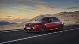 Roter BMW M350 xDrive in Front-Seiten-Ansicht während der Fahrt auf einer Straße in felsiger Berglandschaft.