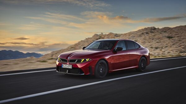 Roter BMW M350 xDrive in Front-Seiten-Ansicht während der Fahrt auf einer Straße in felsiger Berglandschaft.
