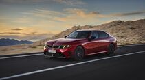 Roter BMW M350 xDrive in Front-Seiten-Ansicht während der Fahrt auf einer Straße in felsiger Berglandschaft.