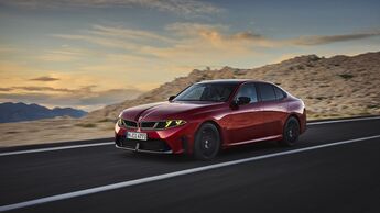 Roter BMW M350 xDrive in Front-Seiten-Ansicht während der Fahrt auf einer Straße in felsiger Berglandschaft.