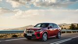 Roter BMW iX2 auf Landstraße, vollelektrisches SUV-Coupé mit neuer Leistungselektronik für das Modelljahr 2026