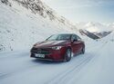 Roter Mercedes CLA fährt auf schneebedeckter Strasse durch ein Gebirgstal, Front schräg im Bild.