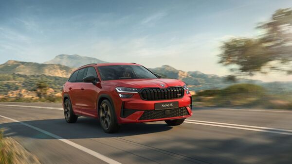 Roter Skoda Kodiaq RS mit Allradantrieb fährt auf Landstraße vor Bergkulisse.