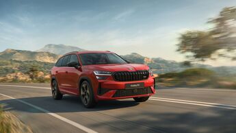 Roter Skoda Kodiaq RS mit Allradantrieb fährt auf Landstraße vor Bergkulisse.