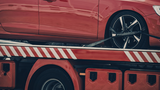 Rotes Auto auf einem Abschleppwagen als Symbol für Abschleppkosten und Standgebühren im Fuhrpark