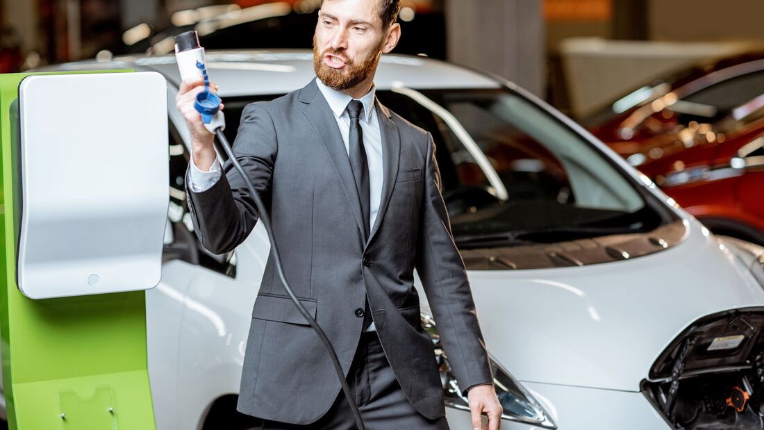 Salesman with electric car charging station in the dealership