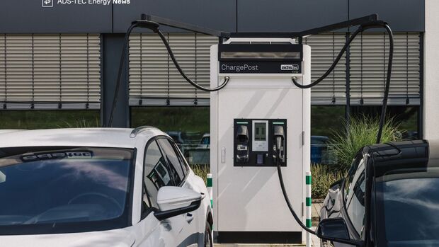 Schnellladesäule von ADS-TEC Energy zwischen zwei Elektrofahrzeugen an einem Unternehmensstandort.