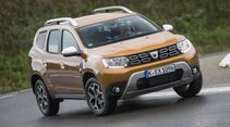 Schräg aufgenommene Frontansicht eines Dacia Duster der zweiten Generation während der Fahrt auf asphaltierter Straße.