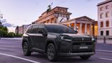 Schwarzer Suzuki Across Plug-in-Hybrid bei der Fahrt auf einer Straße vor dem Brandenburger Tor in Berlin.
