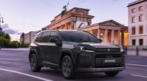 Schwarzer Suzuki Across Plug-in-Hybrid bei der Fahrt auf einer Straße vor dem Brandenburger Tor in Berlin.