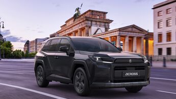 Schwarzer Suzuki Across Plug-in-Hybrid bei der Fahrt auf einer Straße vor dem Brandenburger Tor in Berlin.
