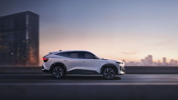 Seitenansicht des Renault Filante während der Fahrt auf einer Straße vor urbaner Skyline bei Abendlicht.
