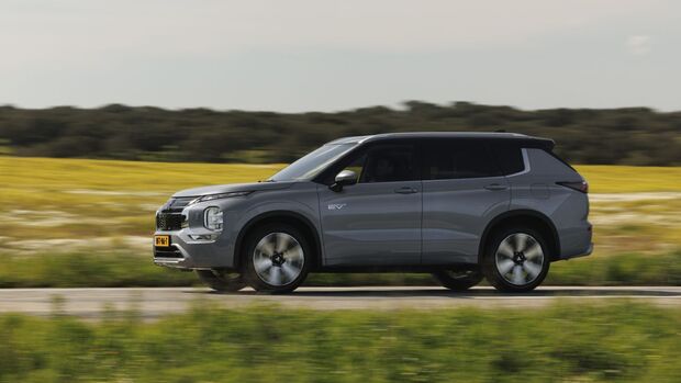 Seitenansicht eines Mitsubishi Outlander Plug-in-Hybrid während der Fahrt durch eine Landschaft.