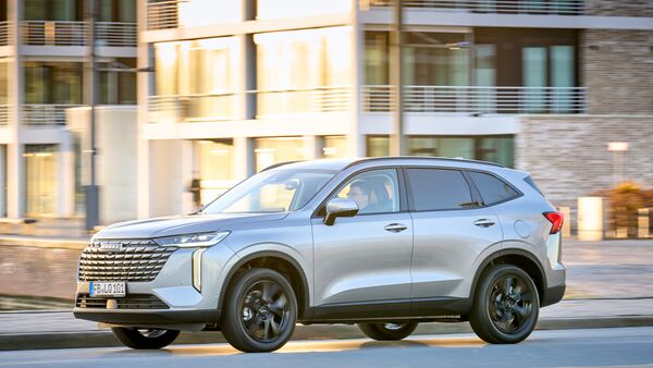 Silberner GWM Haval H6 in Seitenansicht während der Fahrt im städtischen Umfeld.