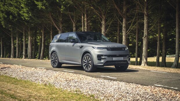 Silberner Range Rover Sport fährt auf einer asphaltierten Straße durch ein bewaldetes Gelände.