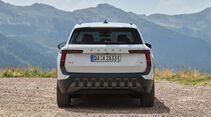 Skoda Epiq 55 in Weiß von hinten vor Bergkulisse, mit T-förmigen Rückleuchten und Modellschriftzug.