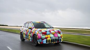 Skoda Epiq Elektro-SUV in Frontansicht mit Tarnfolierung auf nasser Landstraße bei bewölktem Himmel.