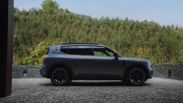 Smart #5 Brabus in seitlicher Ansicht auf gepflastertem Platz vor bewaldeter Landschaft.