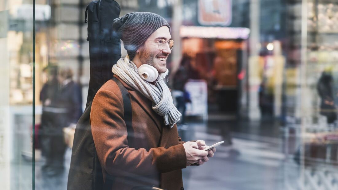 Smiling young man with guitar case and cell phone