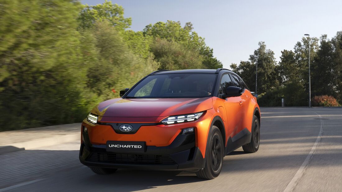Subaru Uncharted 77 FWD Active in Orange bei der Fahrt auf einer Straße, schräg von vorn fotografiert.