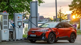 Subaru Uncharted 77 FWD Active in Orange beim Laden an einer Schnellladesäule von Shell Recharge.