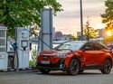 Subaru Uncharted 77 FWD Active in Orange beim Laden an einer Schnellladesäule von Shell Recharge.