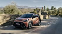 Toyota Aygo X Hybrid auf einer Landstraße vor bergiger Landschaft.
