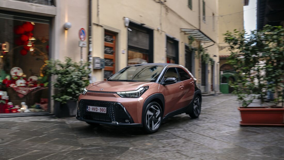 Toyota Aygo X Hybrid fährt durch eine enge Altstadtstraße.