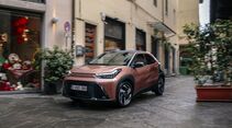 Toyota Aygo X Hybrid fährt durch eine enge Altstadtstraße.