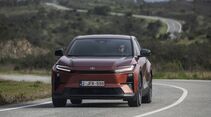 Toyota C-HR+ frontal auf kurviger Straße mit Landschaft im Hintergrund
