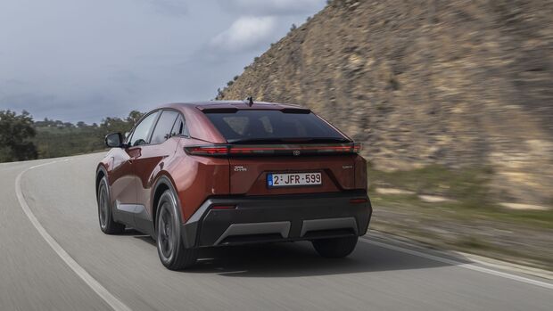 Toyota C-HR+ in Heckansicht auf kurviger Straße während der Fahrt