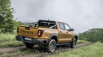 Toyota Hilux auf einem unbefestigten Weg in Heckansicht.
