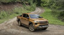 Toyota Hilux auf einer Schotterpiste in einer Kurve im Gelände.